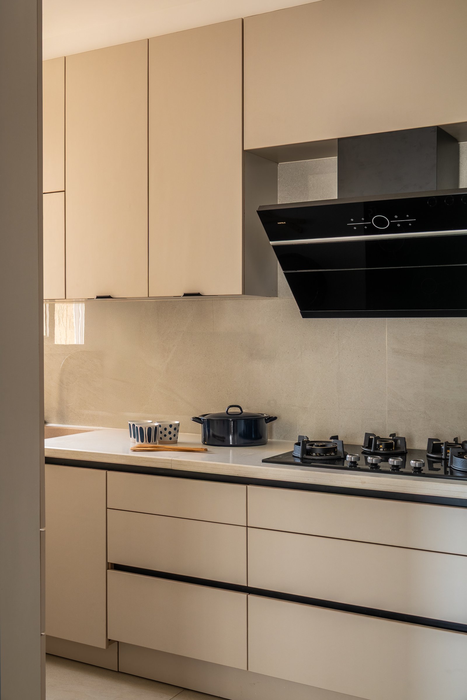 The kitchen holds its function quietly, its warm greige cabinetry and stone-look backsplash stepping back from the home's expressive register