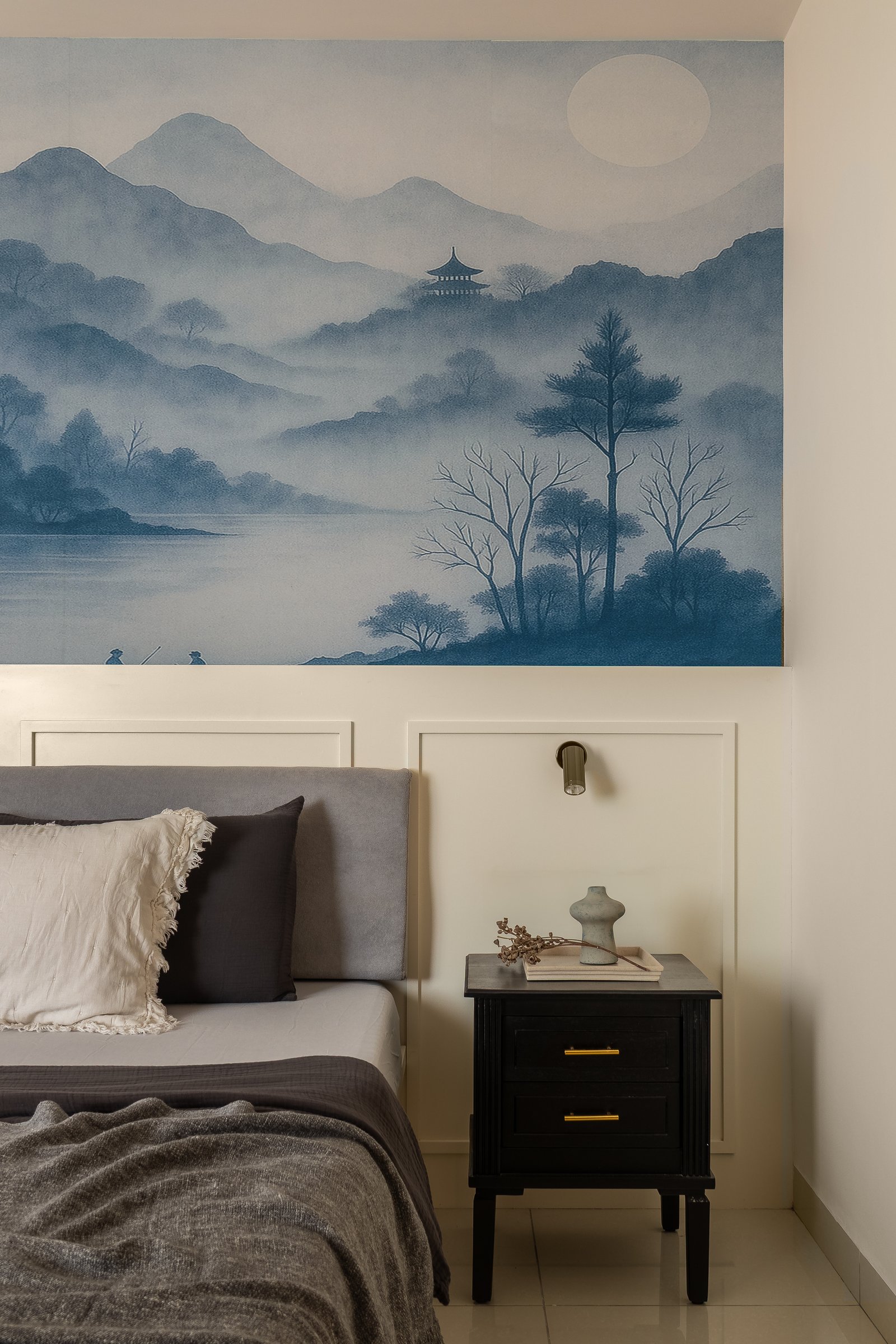 In the master bedroom, an ink-wash mural of misty mountains above a panelled headboard wall sets a contemplative tone distinct from the living spaces