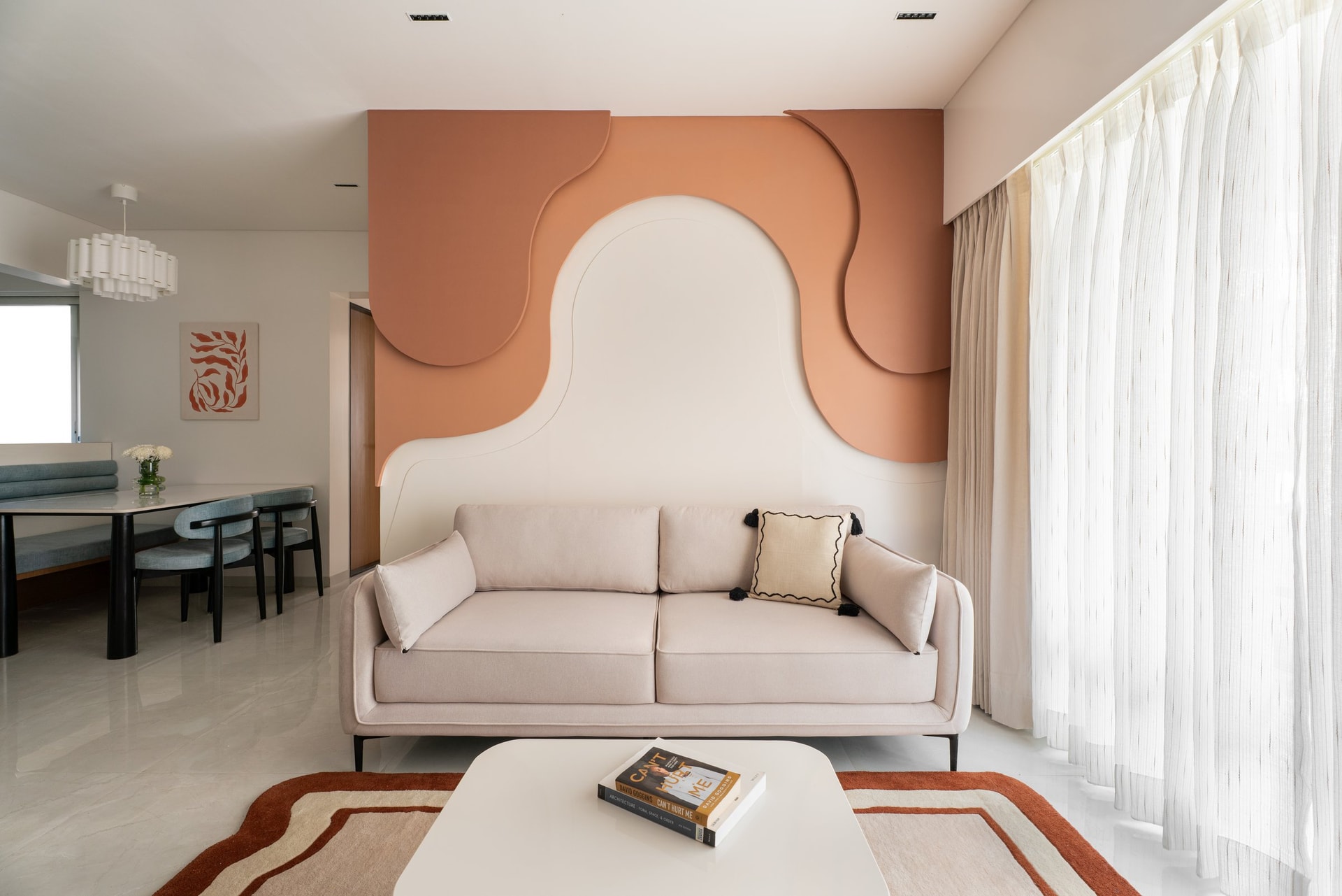 The living room's full-height accent wall, its layered terracotta forms the single boldest gesture in the apartment