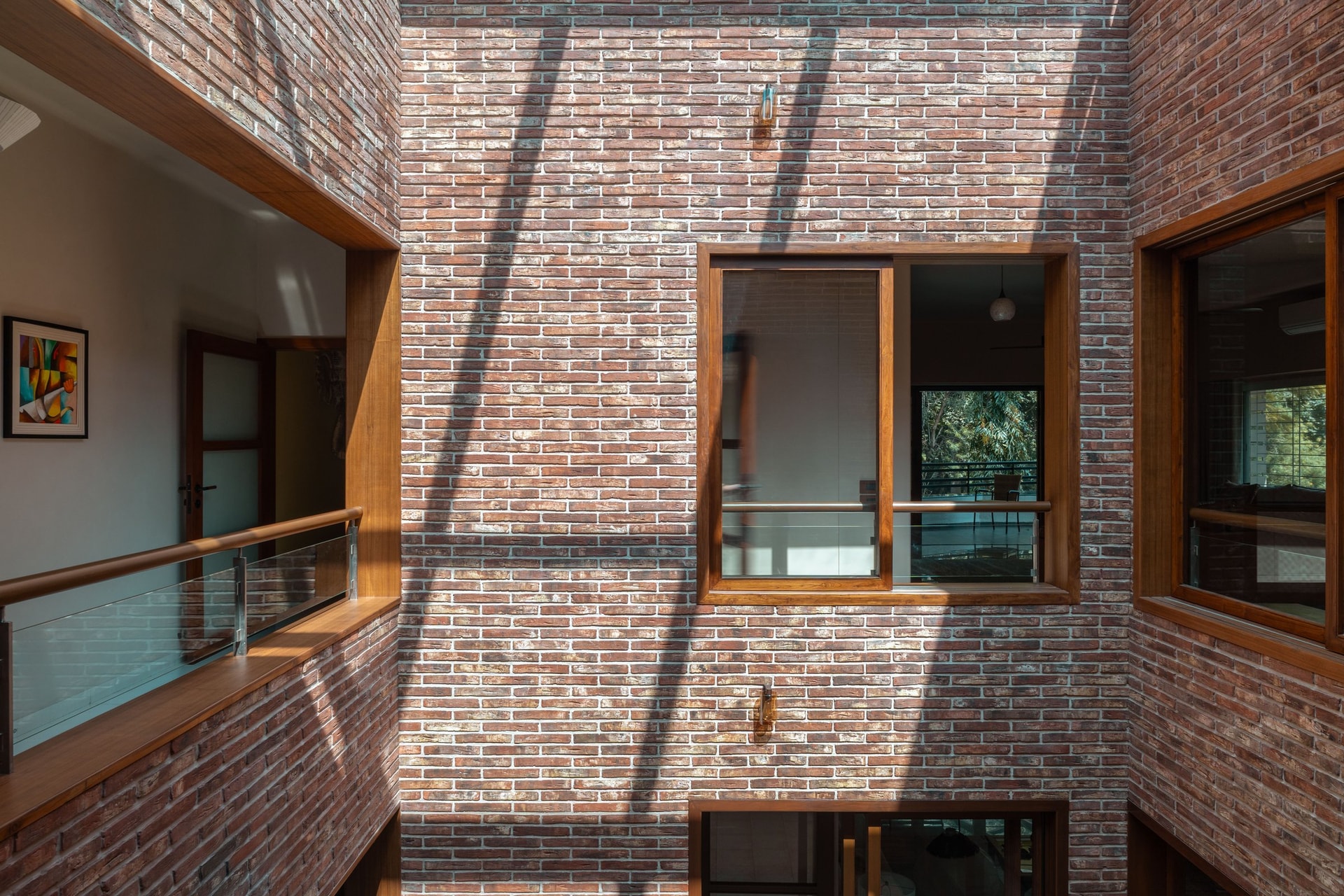 Diagonal shadows from the skylight crawl across the atrium's brick surface, the home's daily light performance