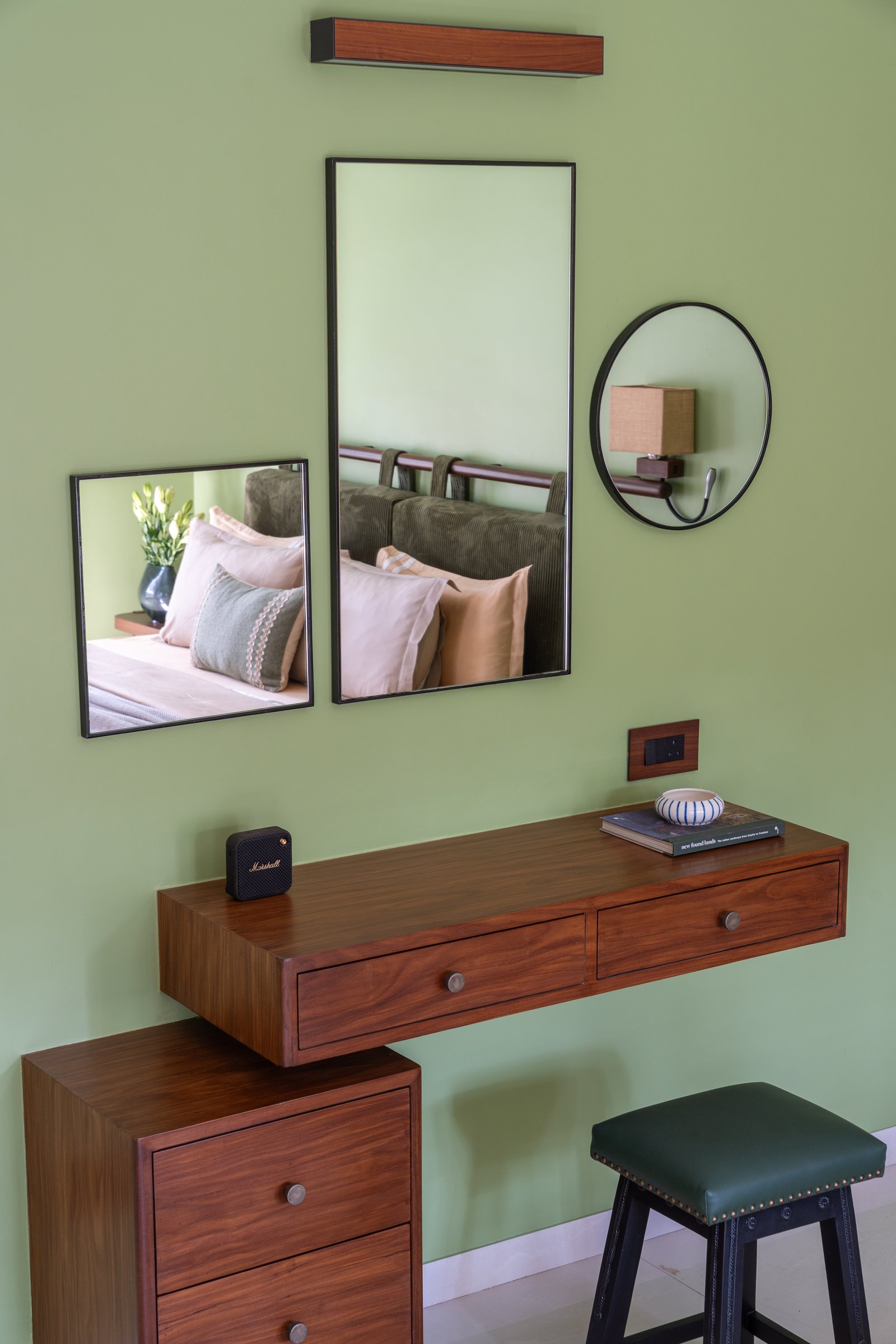 A wall-mounted console and composition of mixed mirrors lend the guest bedroom an informal, collected quality