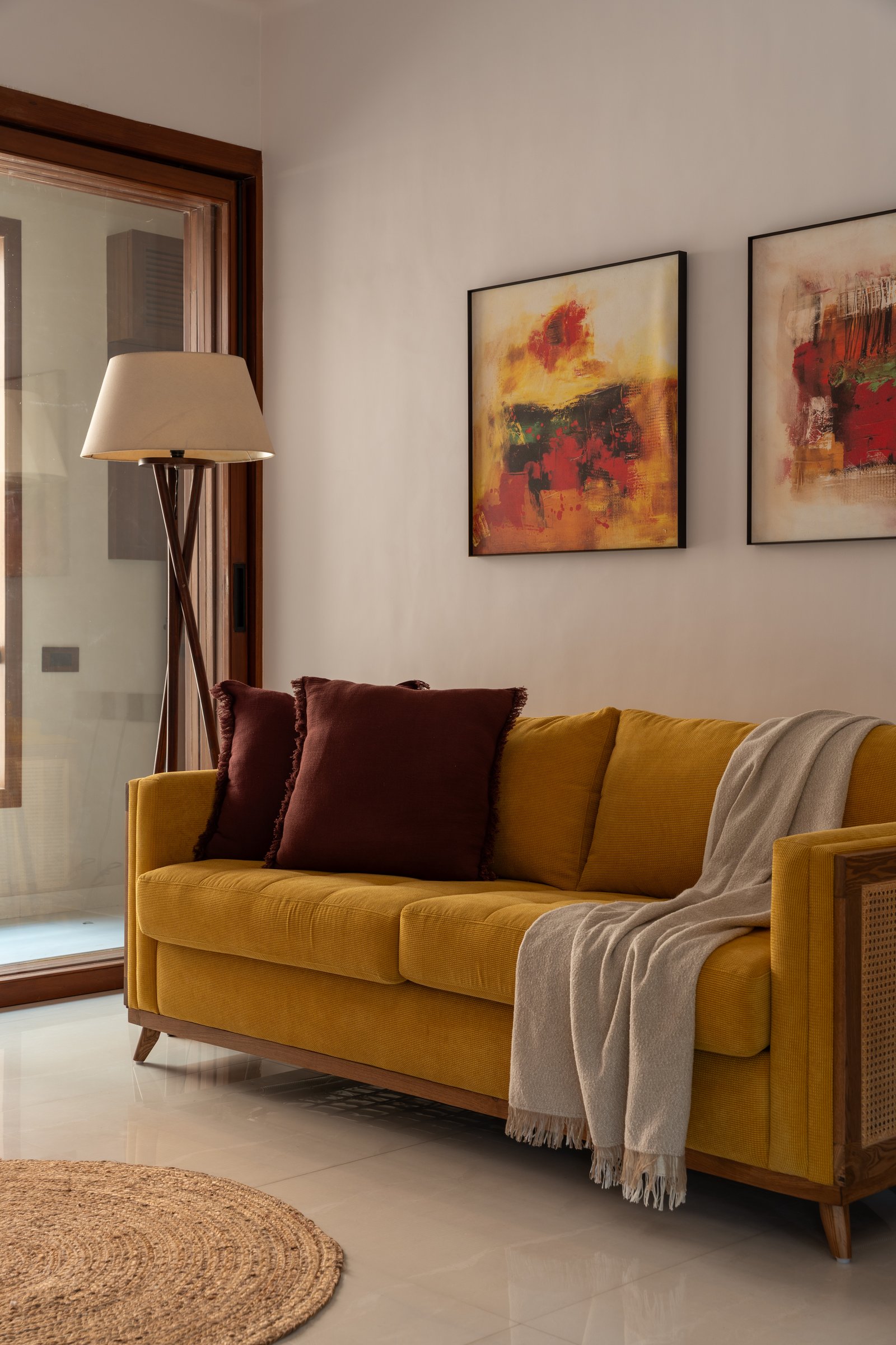 A mustard sofa and abstract paintings in the study's sitting corner, the home's most saturated colour moment