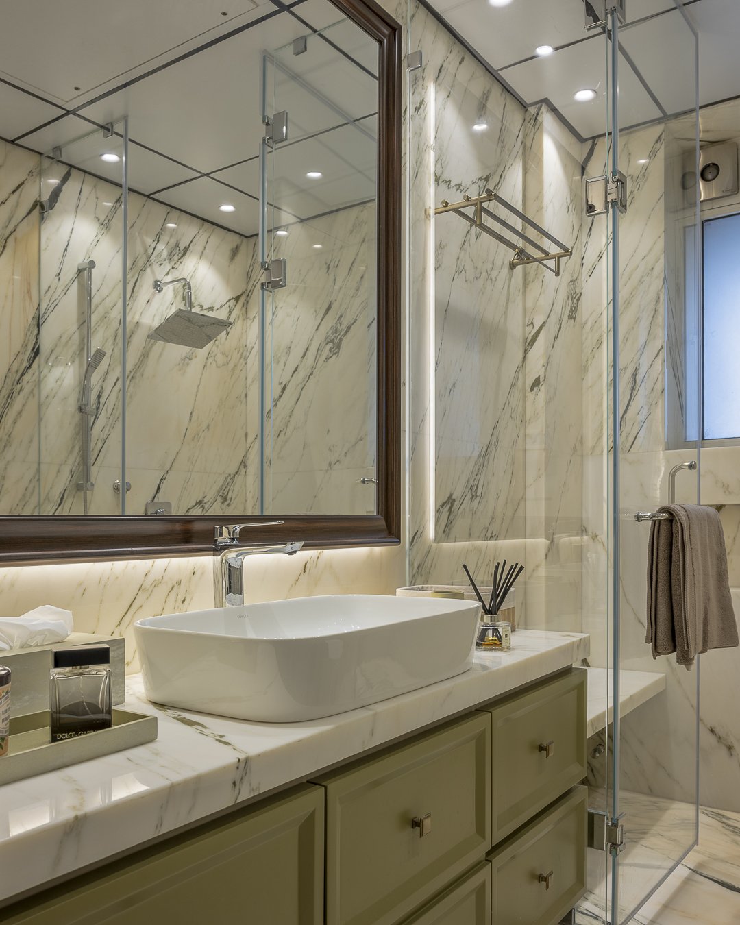 A second bathroom pairs sage green cabinetry with lighter veined marble, extending the home's palette into its most compact spaces